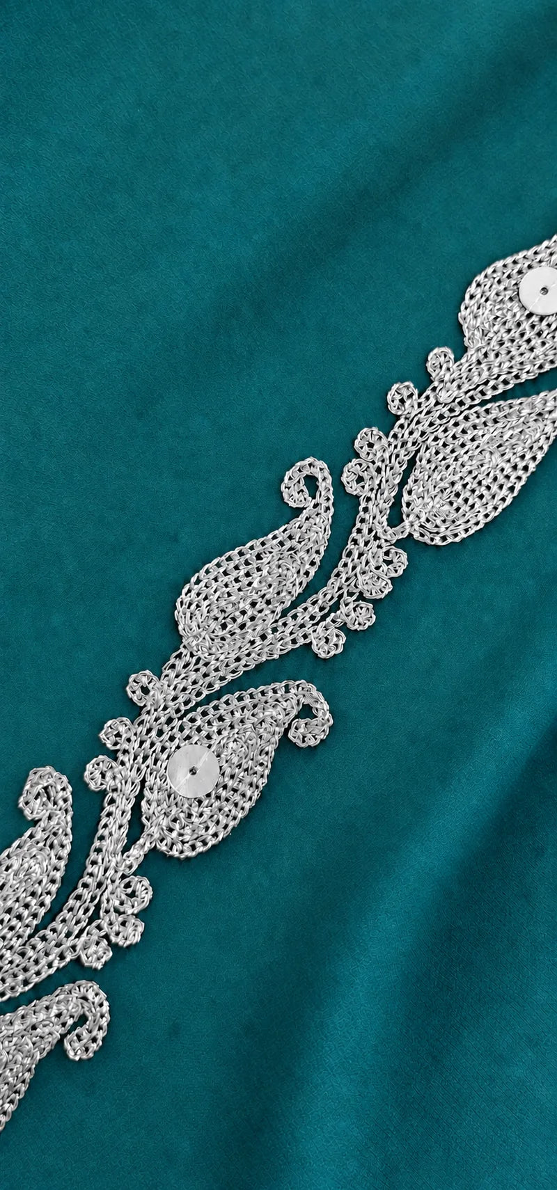 Close-up of silver Zari embroidery on emerald fabric