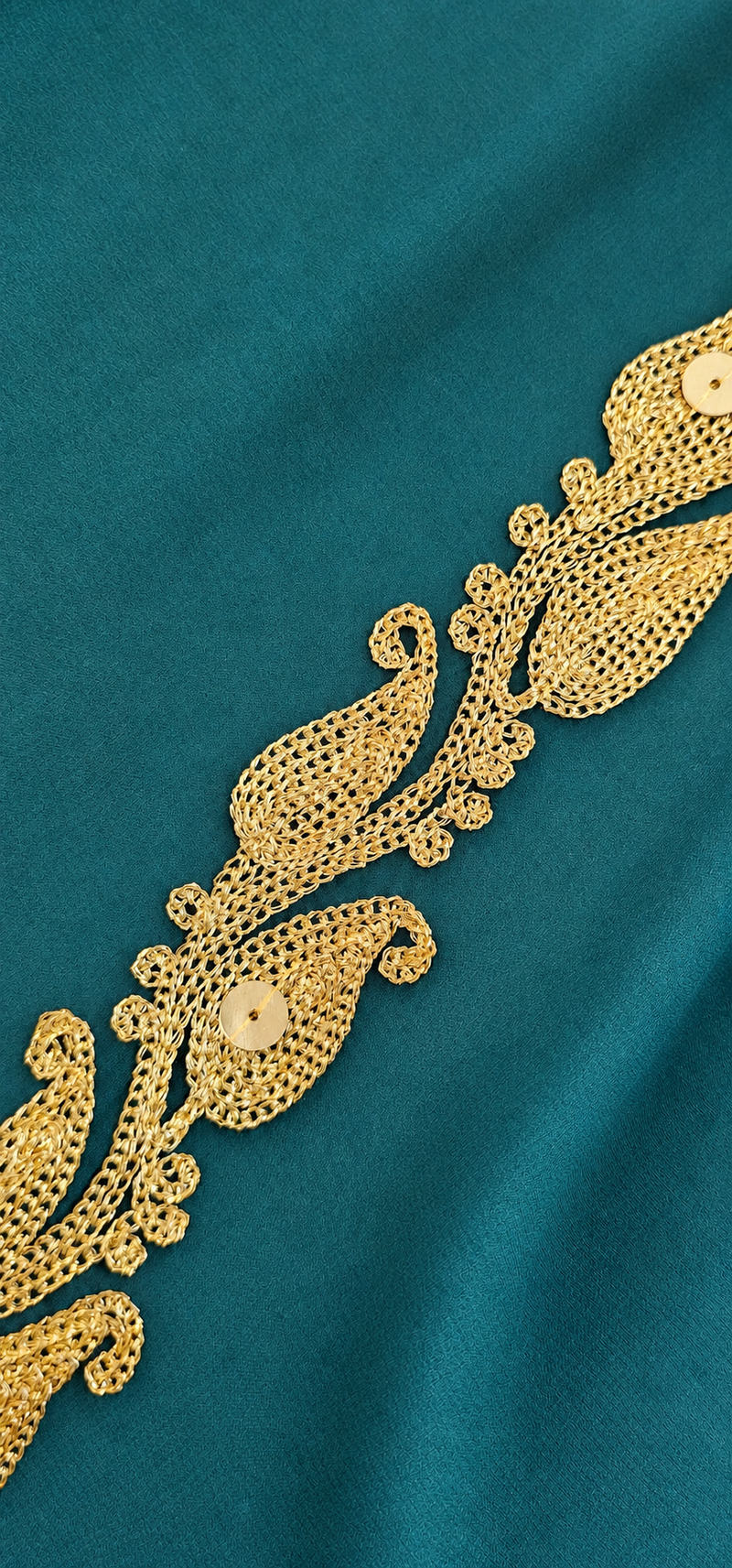Close detail of gold paisley embroidery on emerald silk