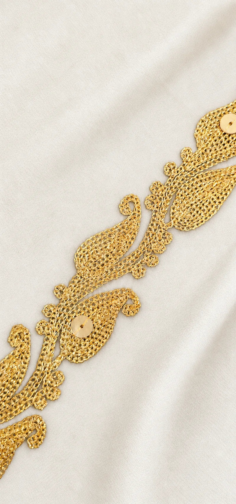 Close-up of gold Zari embroidery on white fabric